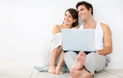 Couple sitting together using laptop